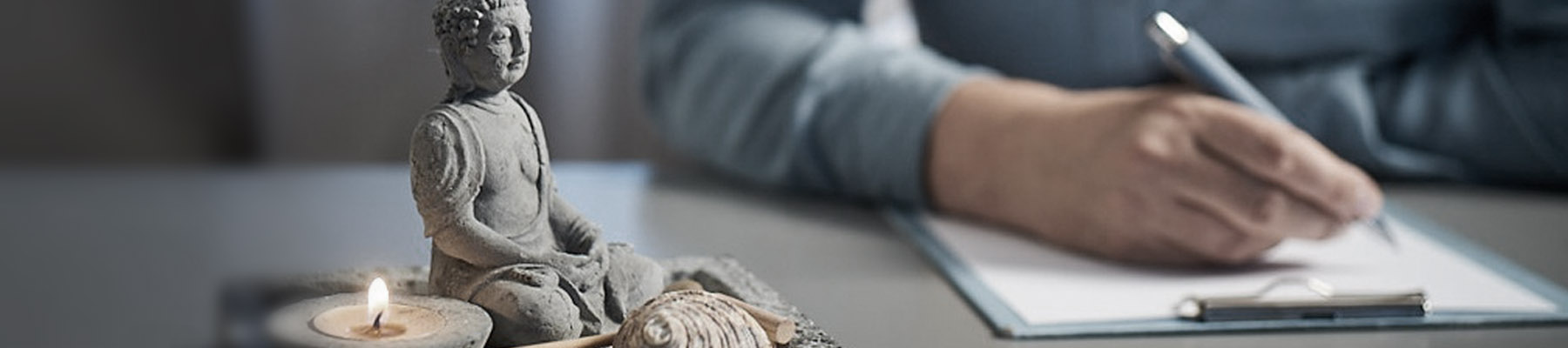 Kontakt Praxis für Psychotherapie und Hypnose kleiner Buddha im Vordergrund und schreibende Hand
